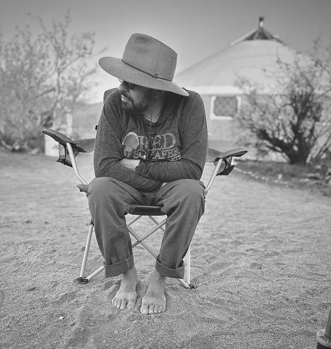A veteran seated barefoot outside the yurt in quiet reflection