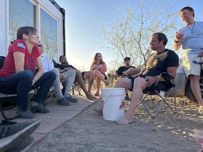 Veterans and volunteers talking together in camp chairs on the patio